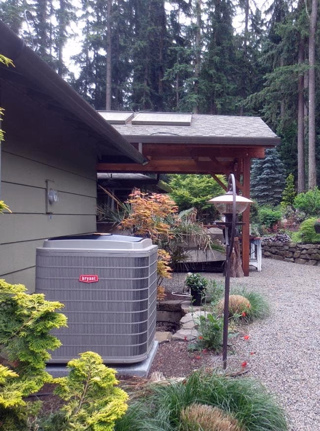 Air conditioner condenser in a side yard with a maple tree