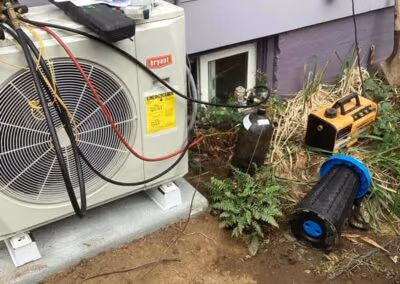 Technician with recovery equipment beside a heat pump outdoor unit