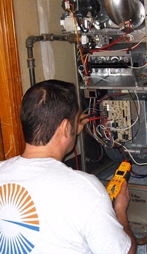 Technician testing a furnace control board with a multimeter
